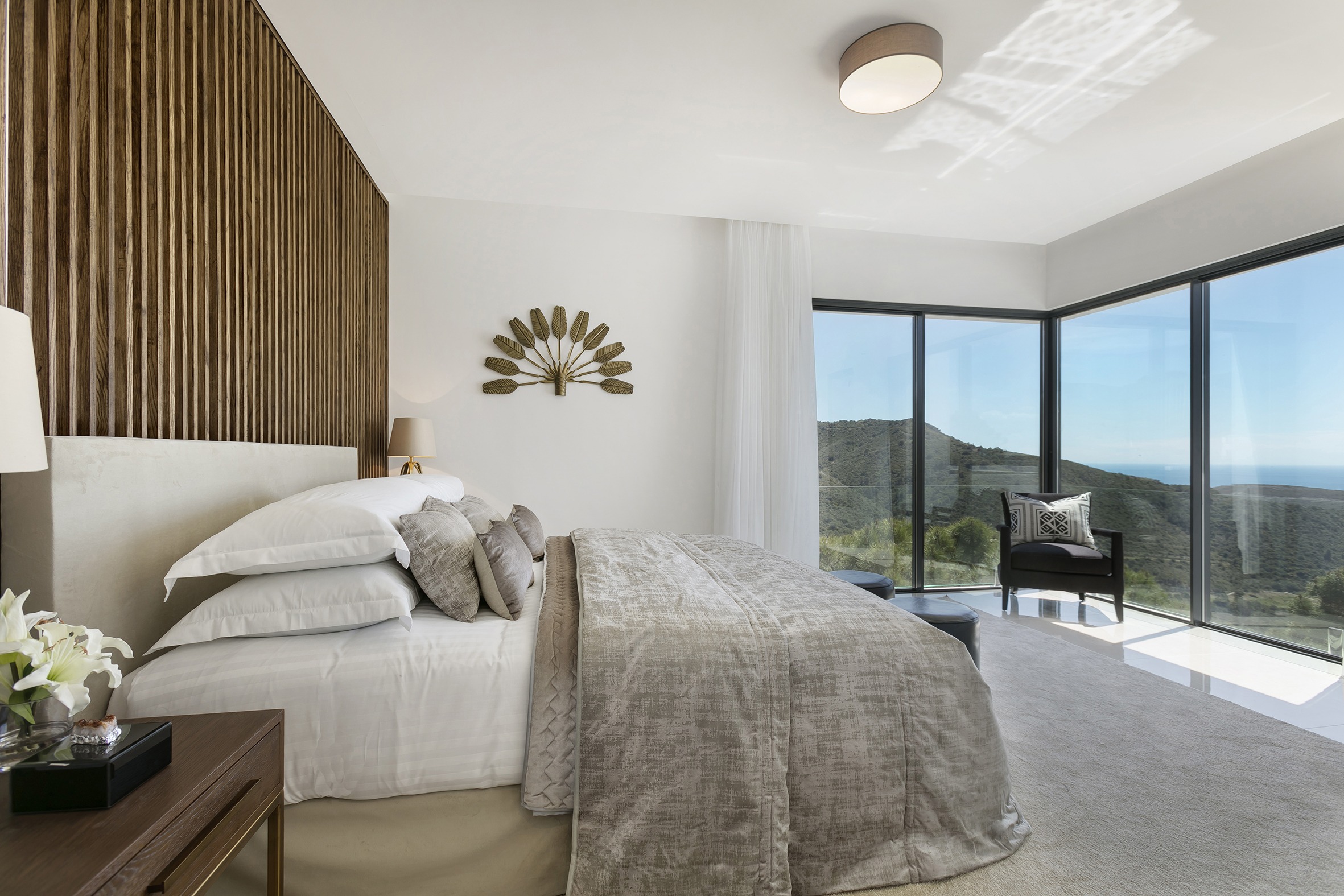 Master bedroom interior design with ocean view and wooden vertical lined wall with and gold - Original Interiors