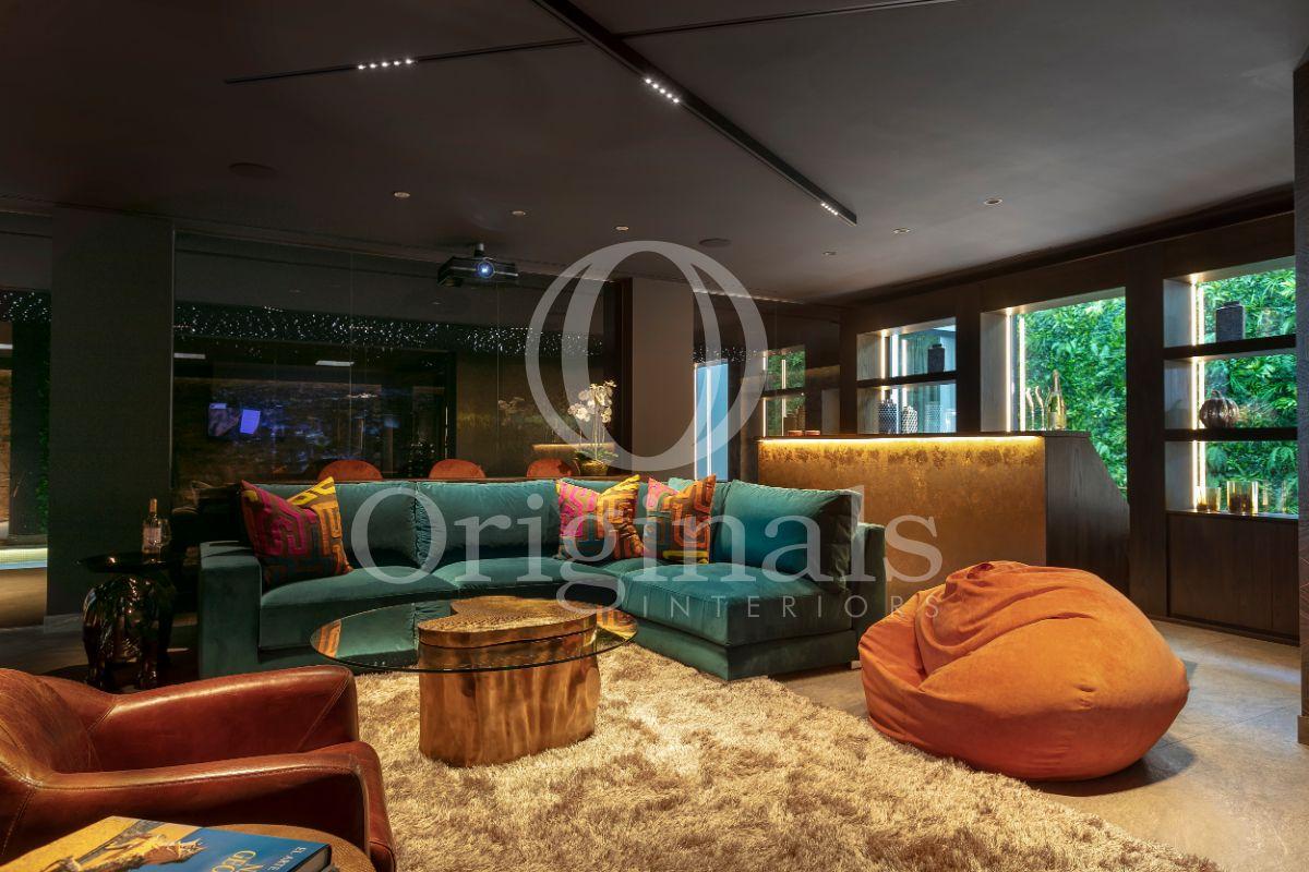 Lounge area with turquoise sofa, orange chairs, a fluffy carpet and living plants background - Originals Interiors