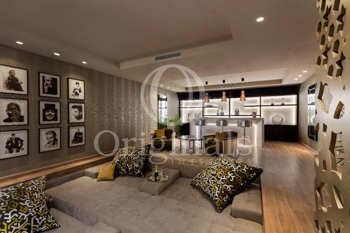Lounge area with a bar with metallic bar stools, grey sofas and artwork on the wall - Originals Interiors