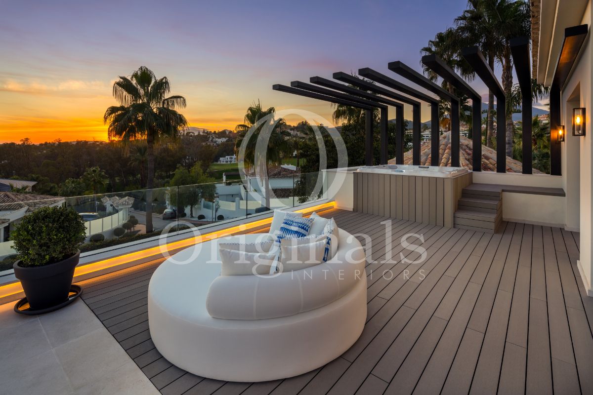 Outside lounge area with wooden platform, a hot tub a round white sofa - Originals Interiors