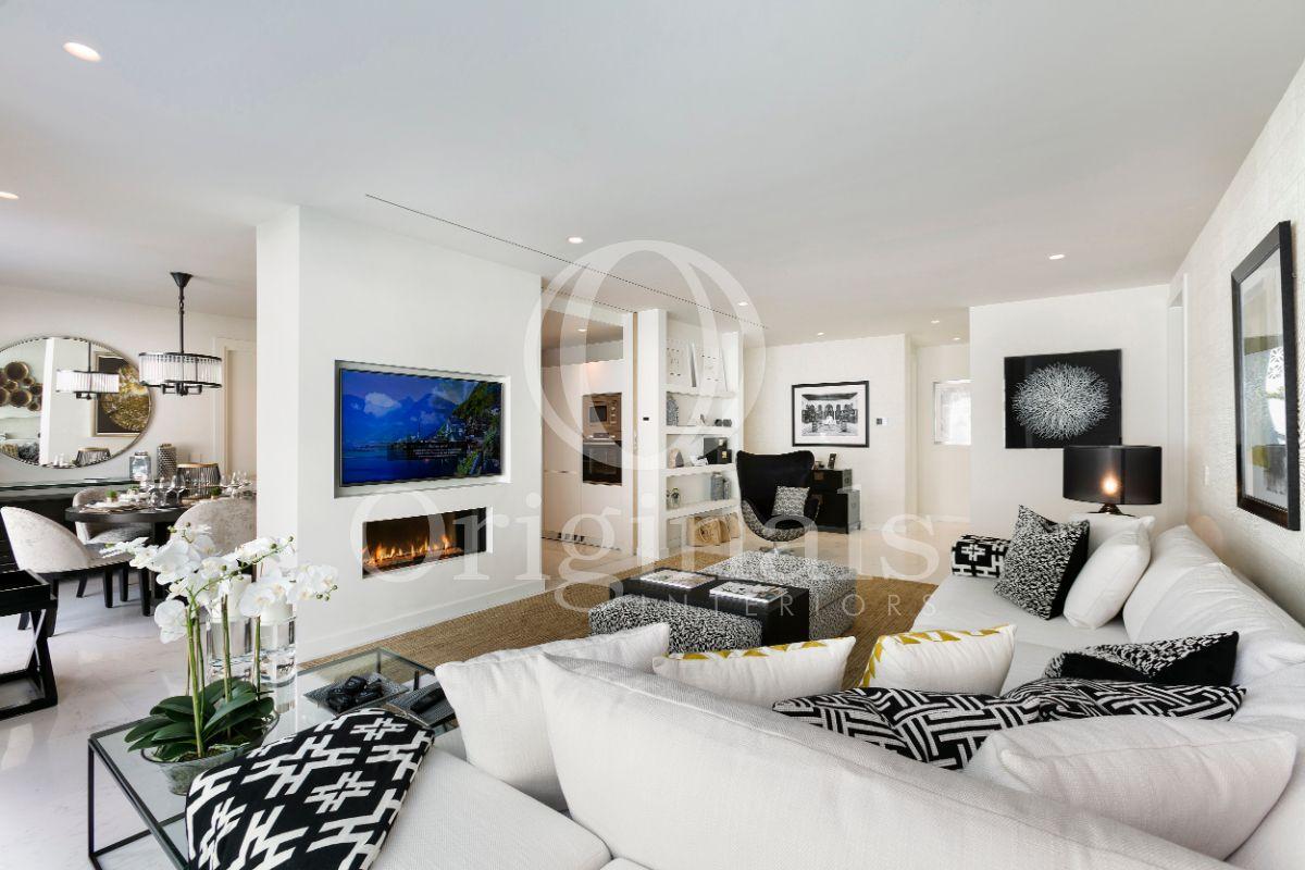 Living room with white sofa, a fire pit, a brown carpet and artwork on the wall - Originals Interiors