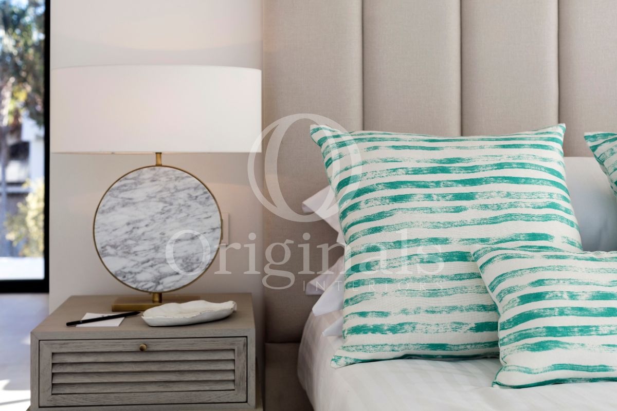 Bed with turquoise and white striped pillows - Originals Interiors