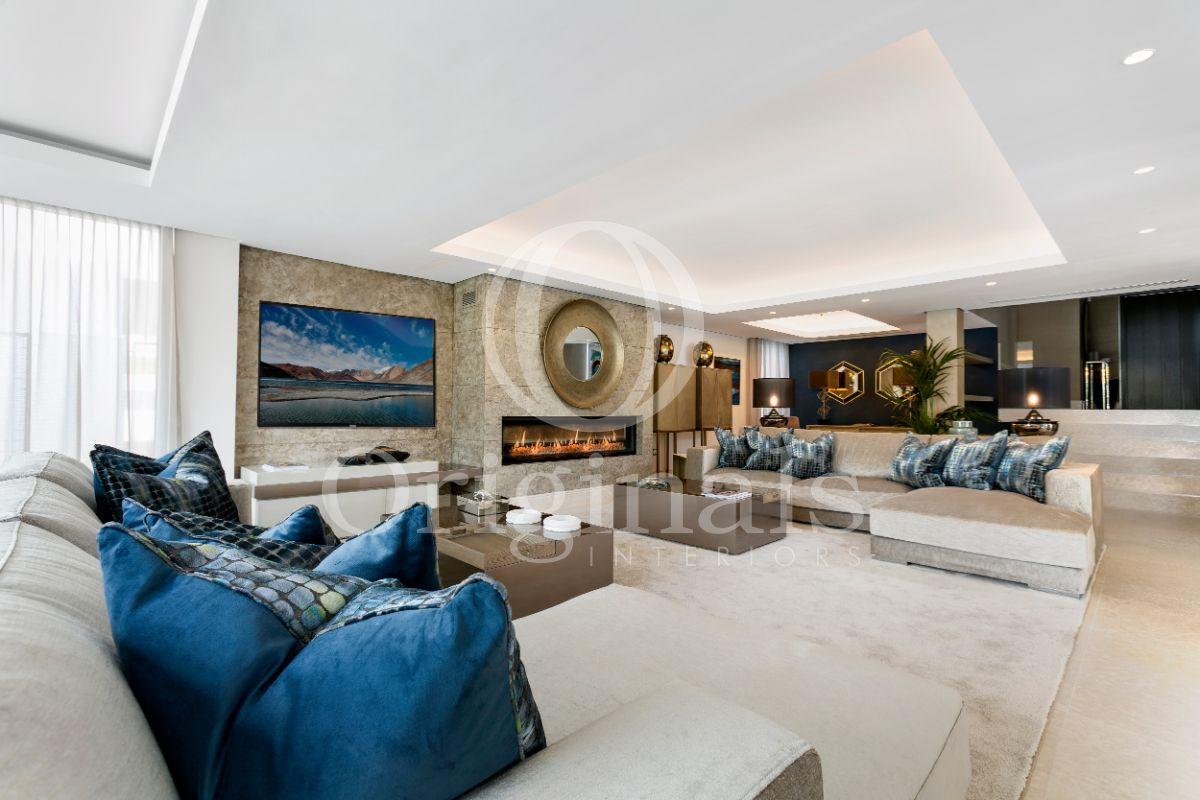 Living area with beige sofas with blue printed cushions and a beige carpet - Originals Interiors