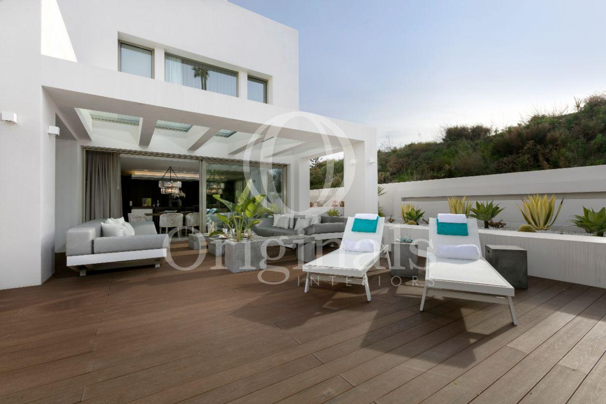Outside lounge area with grey sofas and a wooden floor and white sun loungers- Originals Interiors