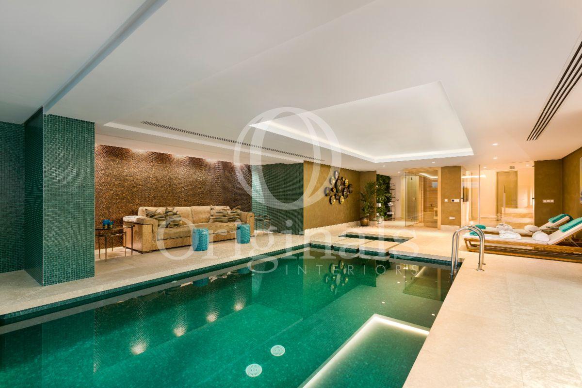 Inside swimming pool with turquoise tiles and a beige sofa - Originals Interiors