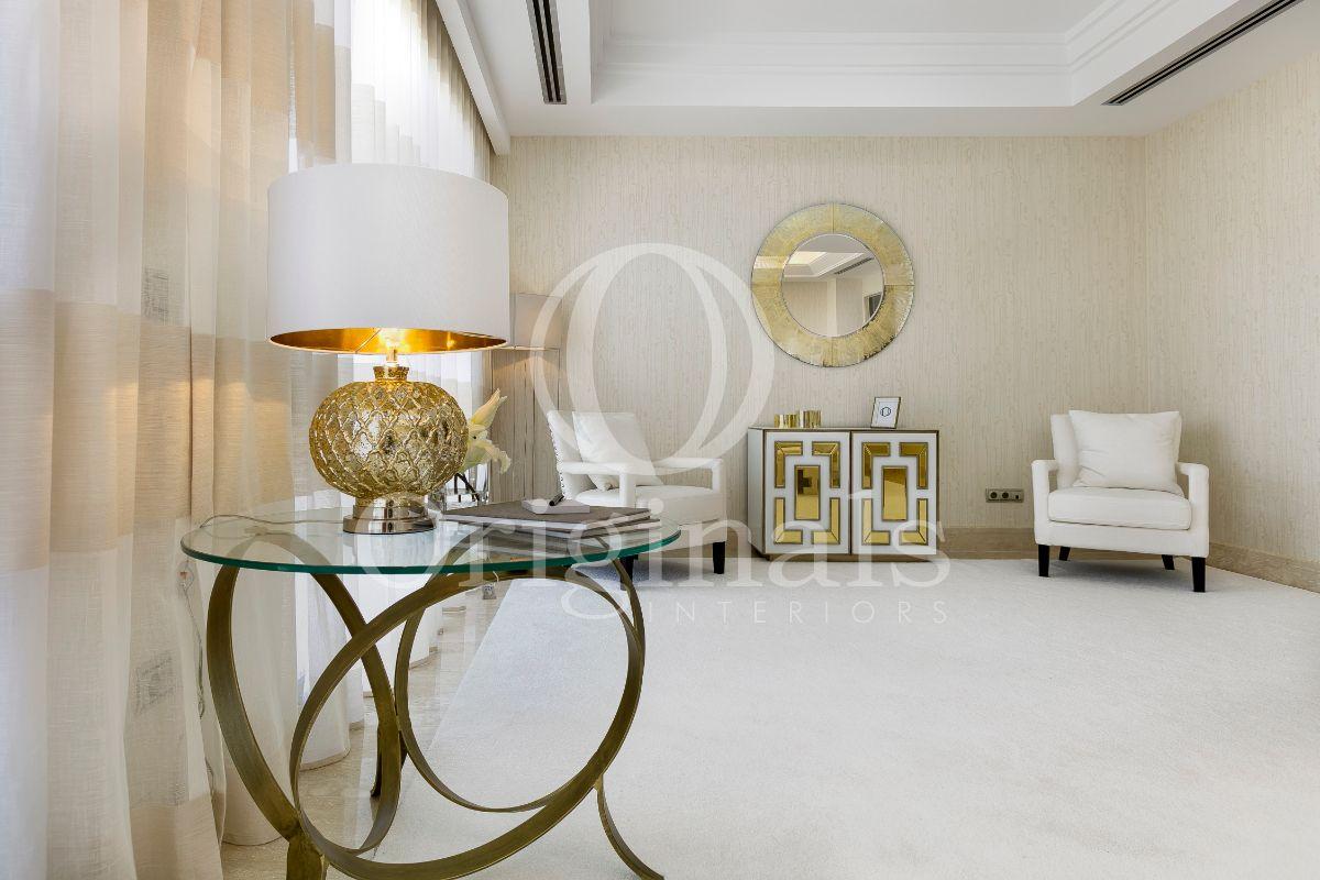 Chamber with little glass table, white sofas and a golden mirror on the wall - Originals Interiors