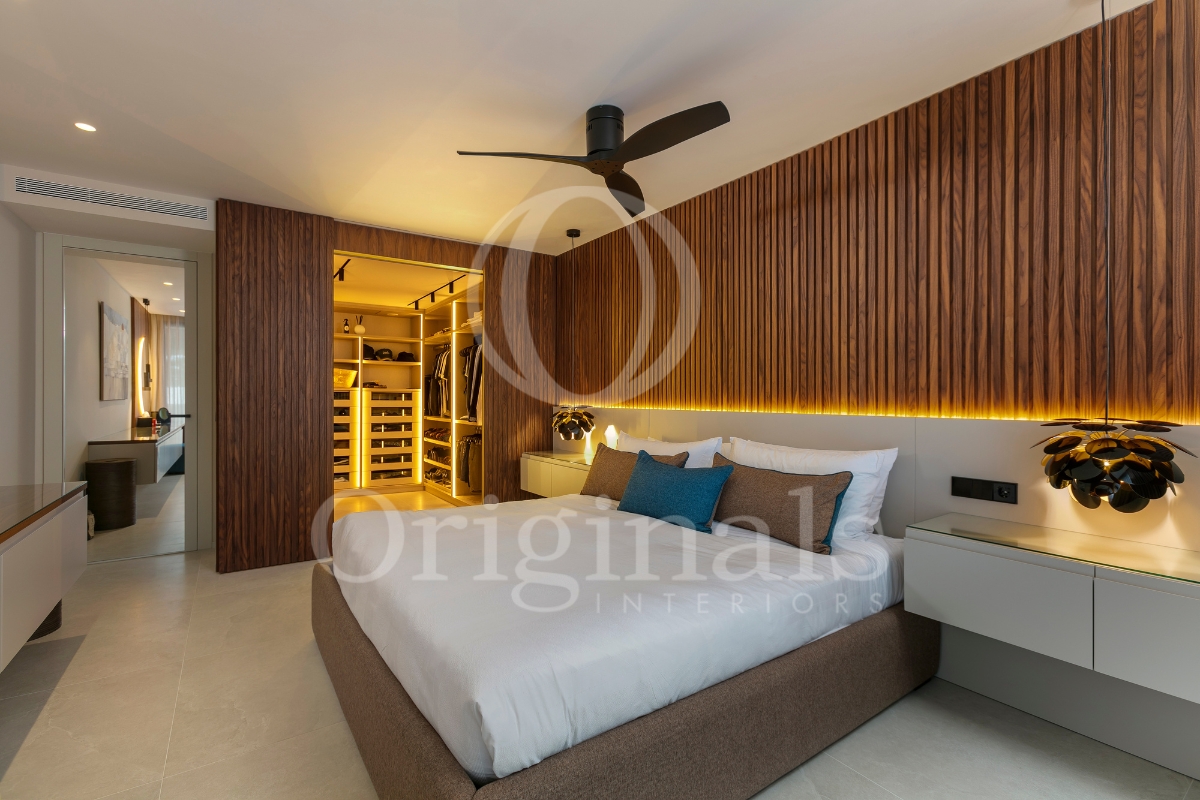 Bedroom with wooden walls, brown and white forniture and a walk in closet - Originals Interiors
